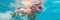 The little girl in the water park swimming underwater and smiling BANNER, LONG FORMAT