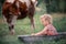 Little girl in a water tub on a green meadow and a cow in the background. Simple rural farm spiritual look.