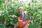 Little girl with watering can is among green plants in a garden