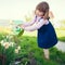 Little girl watering daffodils flowers in the garden