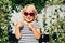 A little girl with wavy blonde hair in sunglasses holds her thumb with a like.