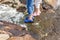 Little girl wearing blue slippers standing on the rocks near a sea. A child in blue shoes perches on the shore