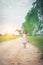 Little girl wearing dress is walking and look away from down rural road.