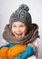 Little girl wearing knitted hat, scarf and sweater, holding a pile of hats,