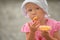 Little girl wearing panama hat is eating orange