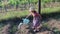 Little girl wears floral dress and white hat. Little girl waters the garden