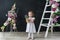 Little girl in a white dress. Baby girl with beautiful flowers stand in flowers room.