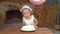 Little girl in white dress blowing out candle, number three on cake.