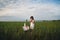 Little girl in white dress drinking milk in green field. Summertime. Evening.