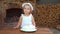 Little girl in white dress and hat blowing out candle, number three on cake.