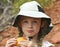 A Little Girl in a White Hat Eating a Peach