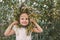 Little girl in white puts on a wreath of flowers on her face