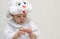 Little girl in a white rabbit costume cleans a quail egg on a light background. A child in a hare mask peels an egg from its shell