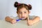 Little girl in white shirt holding bamboo toothbrush and plastic toothbrush.