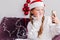 A little girl in a white sweater and Santa Claus hat looks at a mobile phone and says hello. Girl talking by video call