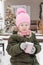 A little girl in winter clothes with a cup of hot cocoa with marshmallows, in the courtyard of a country house decorated