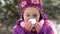 A little girl in winter clothes drinks hot tea from a cup on the street, steam goes.Close-up.