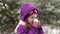 A little girl in winter clothes drinks hot tea from a cup on the street, steam goes.Close-up.