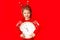 A little girl in winter clothes holds a watch on a red background. New year`s concept, space for text