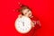 A little girl in winter clothes holds a watch on a red background. New year`s concept, space for text