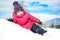 Little girl in winter clothes laying in snow waving and smiling