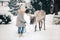 A little girl in winter clothes walks with a deer in a snowy forest. Christmas snow tale