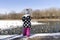 little girl in winter hat, polka-dot jacket and pink pants in winter feeds wild ducks on the pond