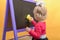 Little girl wipes the blackboard with a damp sponge. The concept of preschool education for children