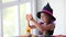 A little girl in a witch costume in a with a slime. Halloween party . handmade. Cute funny girl play with orange slime.