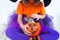 Little girl a witch suit pumpkin of which a kitten