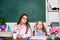 Little girl and woman sit at desk. School education. Studying together. Help with homework. Homework project. Sister