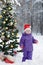 The little girl in the wood near the decorated Christmas tree