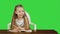 Little girl writes to writing-book on a green screen, chroma key