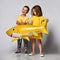 Little girl in a yellow dress wants to pick up a shark balloon from her friend or brother