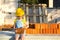 Little girl in a yellow hardhat is playing builder on the construction site of her future home. Expectation of moving, choosing a