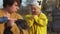 Little girl in a yellow raincoat is petting a black piglet held by a woman