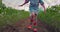 Little girl, young farmer with colorful boots touching tomato plants leaves in greenhouse