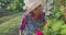 Little girl, young farmer watering and enjoying aroma of roses plants in garden