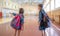 Little girls with backpacks in an empty school gym