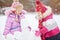 Little girls build wall from snow blocks