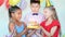 Little girls hold cake while boy blows candles at birthday