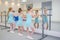 Little girls practicing ballet in studio near barre. Concentrating on exercise, view from back.