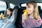 Little girls, sisters are driving in car, eating banana. Traveling on road in safe baby seats with child belts. Fun family trip,