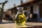 Little glass pitcher with handmade olive oil on the table against village background. Generative AI