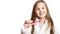 Little happy beautiful preschooler girl brushes her teeth with a pink toothbrush smiling looking at the camera on a white