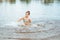 Little happy girl plays with water and splashes of water in the sea