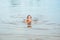 Little happy girl plays with water and splashes of water in the sea