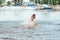 Little happy girl plays with water and splashes of water in the sea