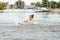 Little happy girl plays with water and splashes of water in the sea