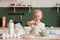 Little happy girl prepares dough in the kitchen. Child pastry chef in the kitchen